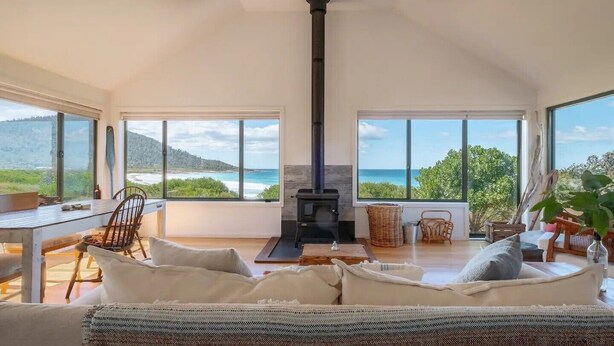 A modern living room with large windows, a fireplace, and a view of the sea. - Silver Moon at Half Moon Bay - Paradise! (Glamorgan-Spring Bay)