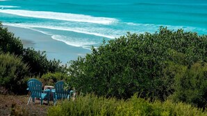 A beach with turquoise waters, a chair, and a table. - Silver Moon at Half Moon Bay - Paradise! (Glamorgan-Spring Bay)