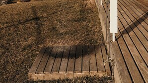 Une terrasse en bois dotée d’une douche, offrant une vue sur un paysage verdoyant et des montagnes lointaines.