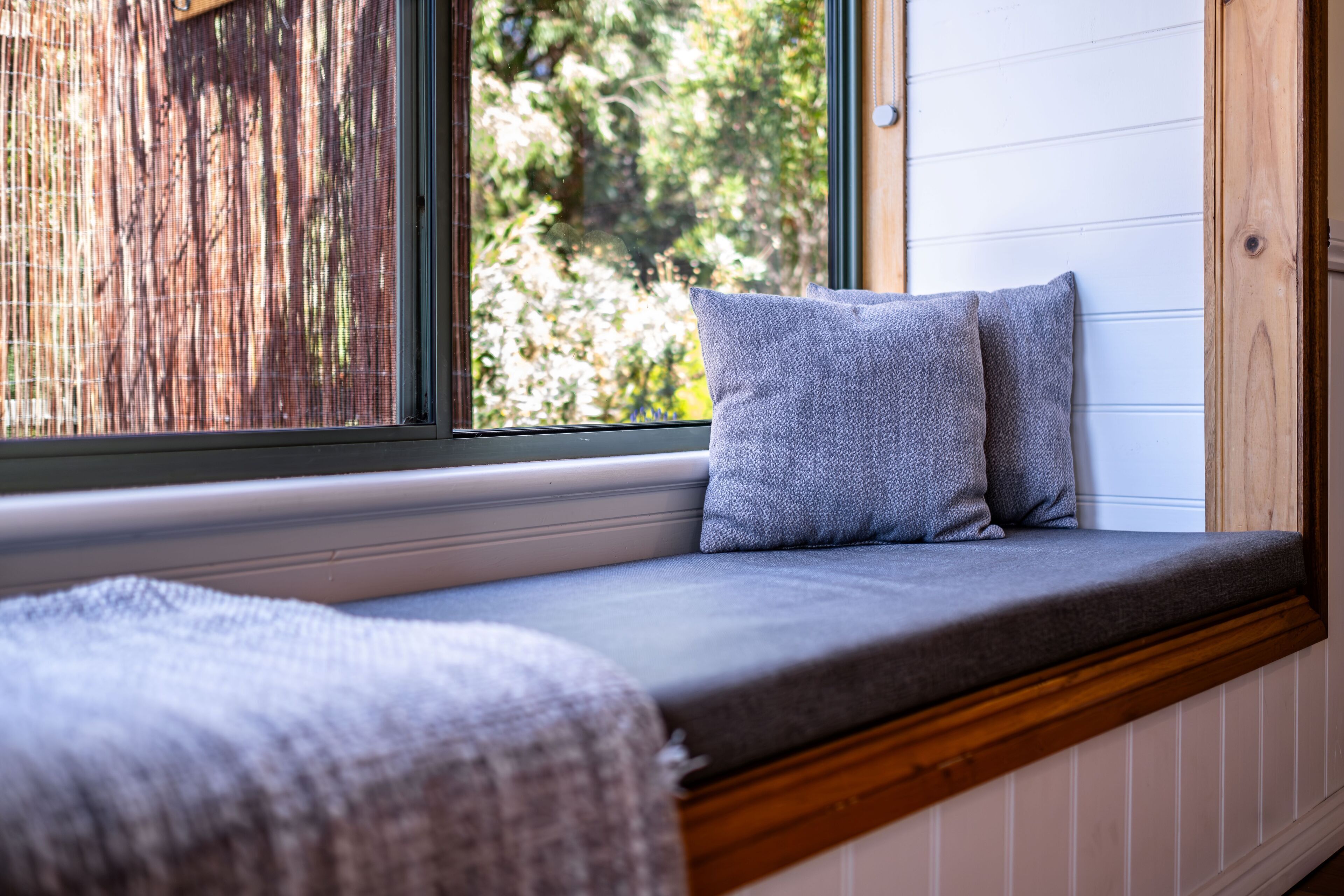 A window seat with a cushion and a blanket.