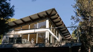 A modern house with a large glass window area and a sloped roof.