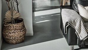 Una cuina moderna amb zona de menjador, que inclou una taula de fusta, cadires i un llum penjant.