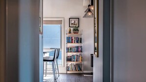 A narrow hallway with a bookshelf, a dining area with chairs, and a window with a view. - Ocean Sunrise - Beautiful views! (Glamorgan-Spring Bay)