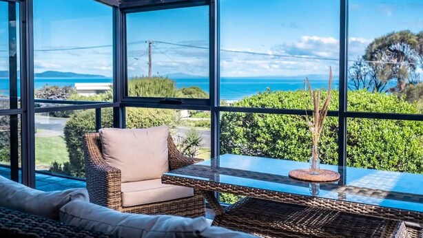 Una habitación moderna con ventanas amplias que ofrecen vistas al mar y a las colinas.