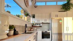 A modern kitchen with white cabinetry, a built-in oven, and a refrigerator. - Viola - A coastal holiday retreat! (Glamorgan-Spring Bay)