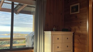 Habitación de cabaña de madera con cama, cómoda y ventana con vistas al paisaje.