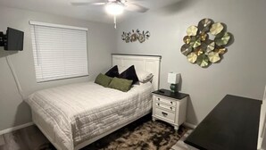 A bedroom with a bed, a ceiling fan, a wall-mounted light, a bedside table, a rug, and a dresser. - Beautiful peaceful quiet country living 

 (Holtville)