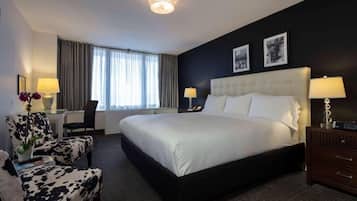 A hotel room with a large bed, a desk, a chair, a dresser, and two lamps.