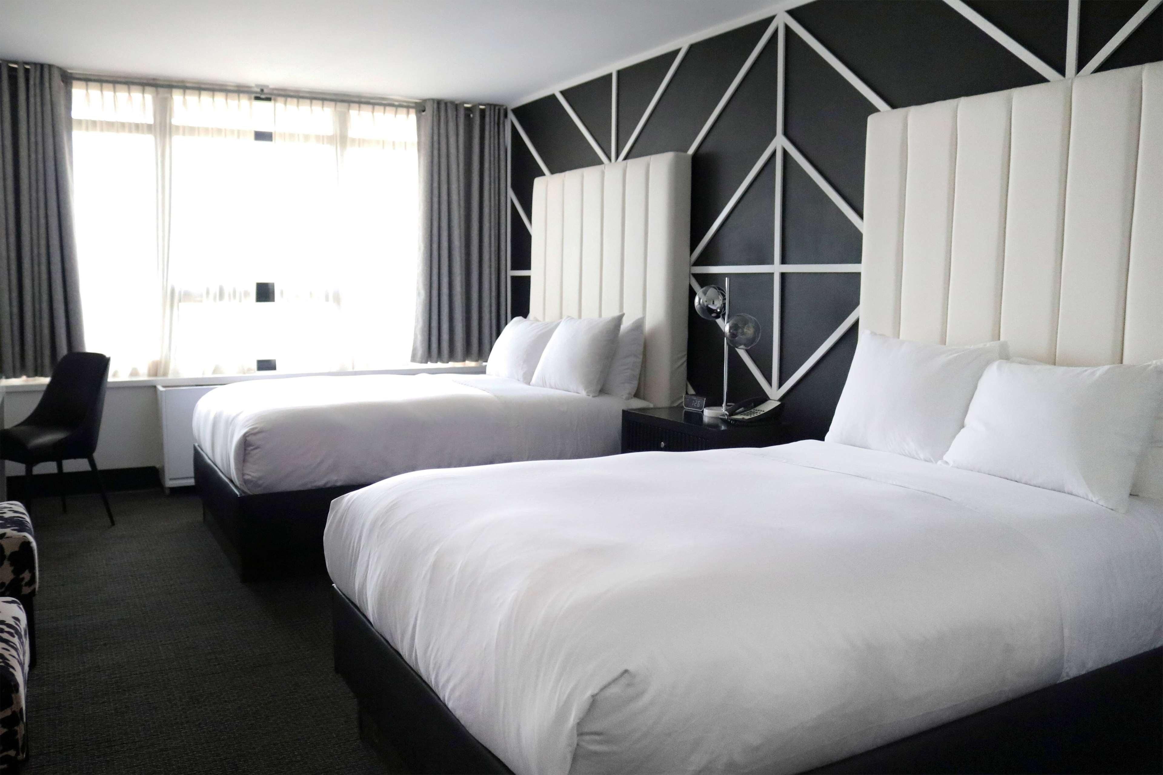 A hotel room with two beds, a desk, and a chair.
