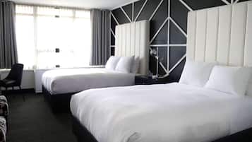 A hotel room with two beds, a desk, and a chair.