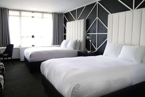 Una camera d'albergo con due letti, una scrivania e una sedia.