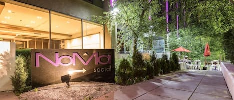 A building entrance with a sign reading "NOVA social" and a pathway leading to outdoor seating.