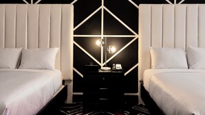 A modern hotel room with two beds, a central nightstand with a lamp, and a geometric wall design. - Hotel Noma Trademark Collection By Wyndham (New Rochelle)
