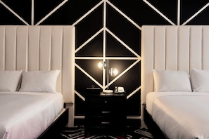 A modern hotel room with two beds, a central nightstand with a lamp, and a geometric wall design. - Hotel Noma Trademark Collection By Wyndham (New Rochelle)