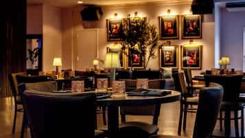 A restaurant with round tables, chairs, and framed pictures on the wall.