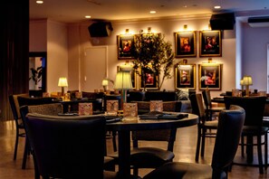 Un ristorante con tavoli rotondi, sedie e quadri appesi alle pareti.