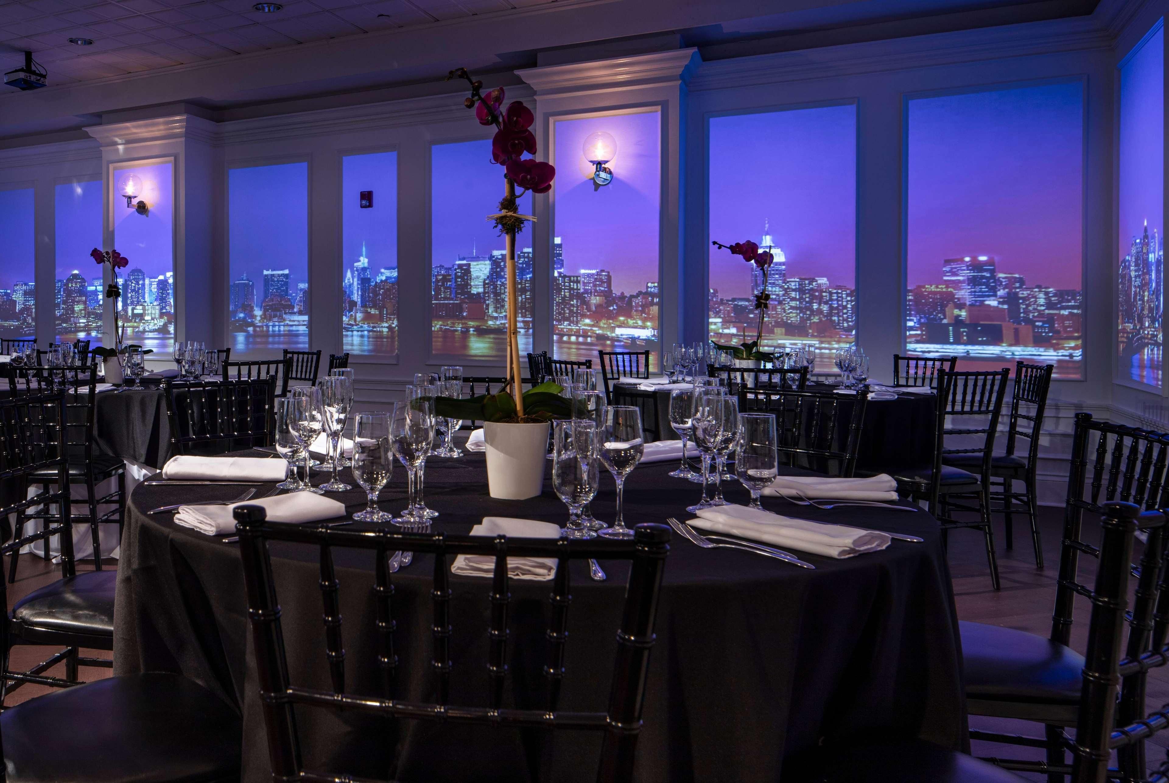 A restaurant with tables set for dining, featuring a cityscape view through large windows.