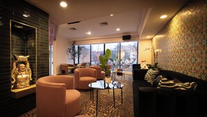 A modern lounge area with a sofa, armchairs, and a patterned carpet. - Hotel Noma Trademark Collection By Wyndham (New Rochelle)
