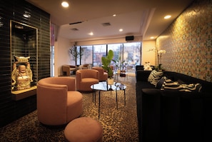 A modern lounge area with a sofa, armchairs, and a patterned carpet. - Hotel Noma Trademark Collection By Wyndham (New Rochelle)