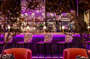A bar area with multiple shelves of bottles, bar stools, and ambient lighting. - Hotel Noma Trademark Collection By Wyndham (New Rochelle)