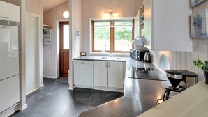 Et moderne køkken med hvide skabe, en sort bordplade og en kaffemaskine.