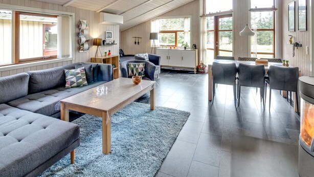 En rummelig opholdsstue med højt til loftet, en sofa, et spisebord og en pejs.