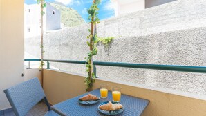Een balkon met een ontbijttafel, twee croissants en twee glazen sinaasappelsap.