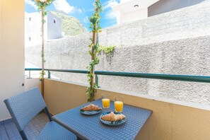 A balcony with a table set for breakfast, two croissants, and two glasses of orange juice. - Sea & Mountain by Atlantic Holiday (Porto Moniz)
