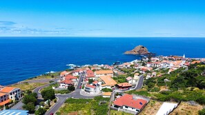 A coastal town with a prominent rocky island, a mix of residential buildings, and a clear view of the ocean. - Sea & Mountain by Atlantic Holiday (Porto Moniz)