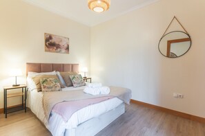 A neatly made bed with pillows, a bedside lamp, and a folded towel on a wooden floor. - Sea & Mountain by Atlantic Holiday (Porto Moniz)