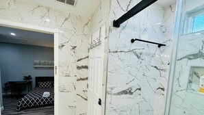 Een moderne badkamer met marmeren wanden en een douchehoek.
