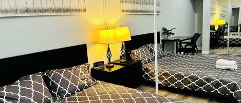 A hotel room with two beds, a large mirror, a desk, and a chair.