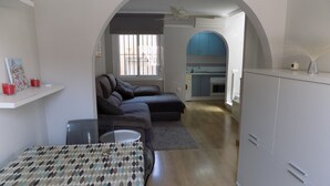 Un espace de vie compact comprenant un coin repas, un canapé et une kitchenette.