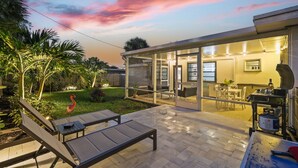 Une maison moderne dotée d’un patio entièrement vitré, de mobilier d’extérieur et d’un jardin bien entretenu.
