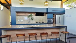 A modern kitchen with a central island, bar stools, and pendant lighting.
