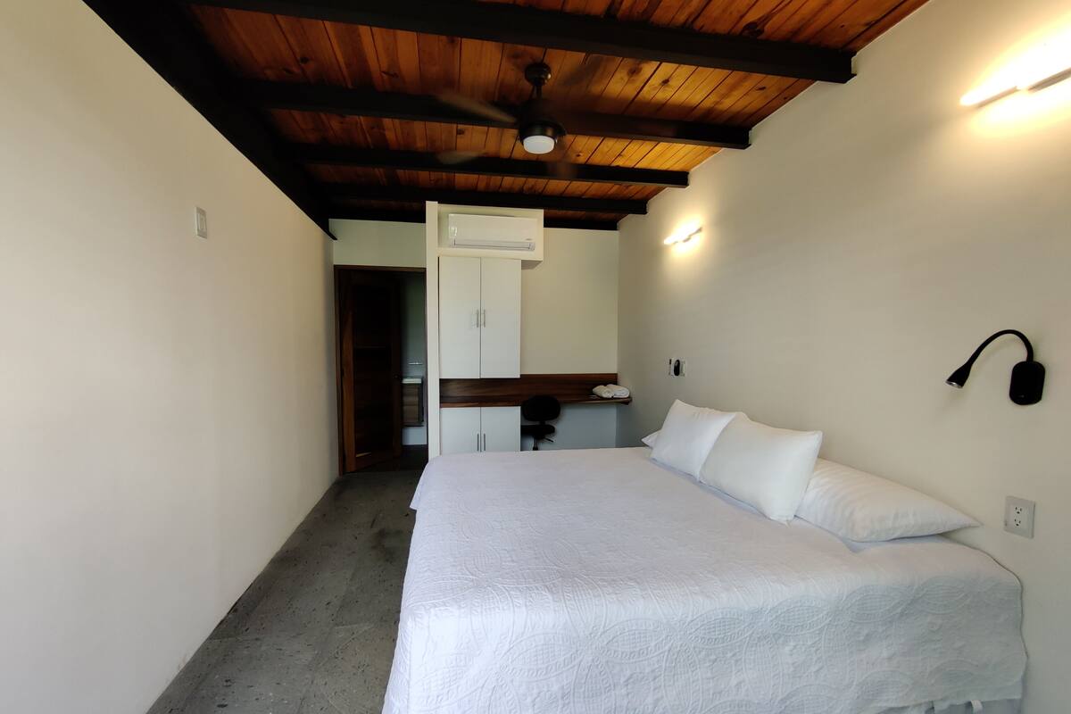 Een slaapkamer met een bed, een kledingkast, een bureau en een plafondventilator.