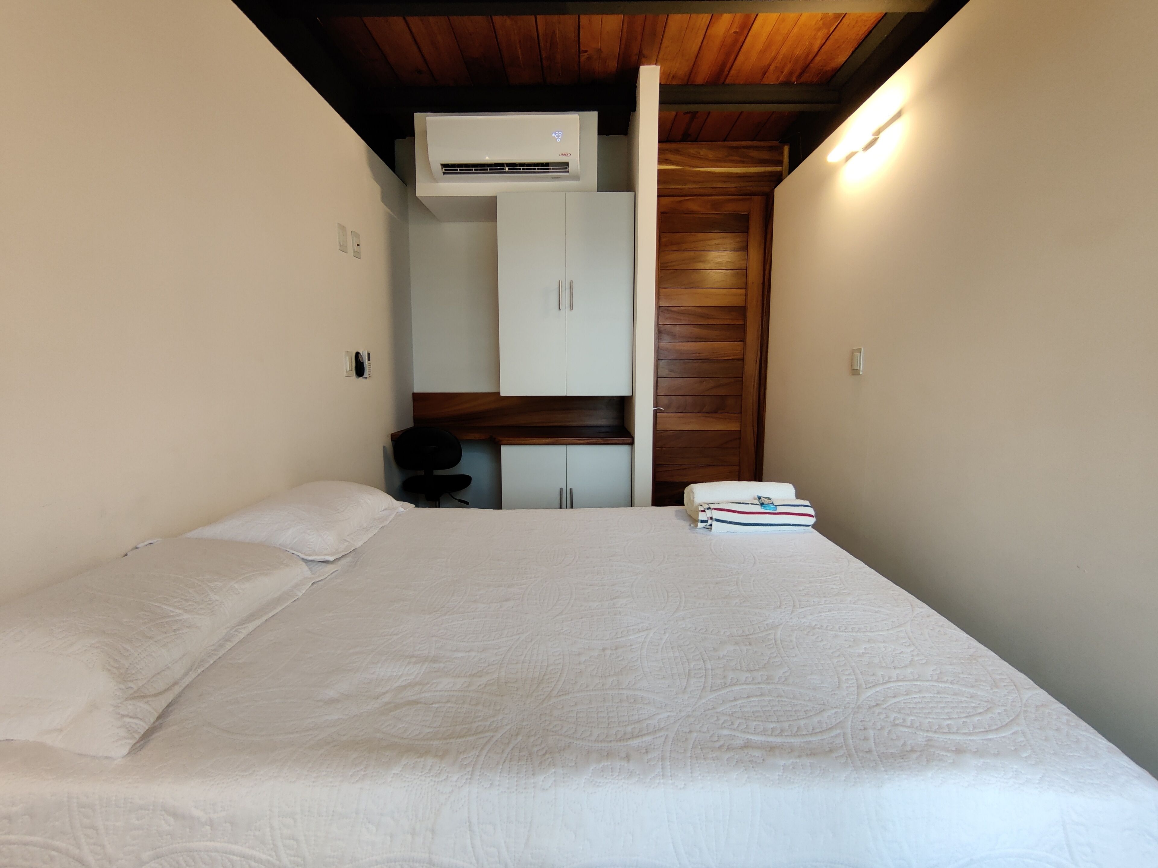 Un dormitorio con cama, armario, escritorio y aire acondicionado.