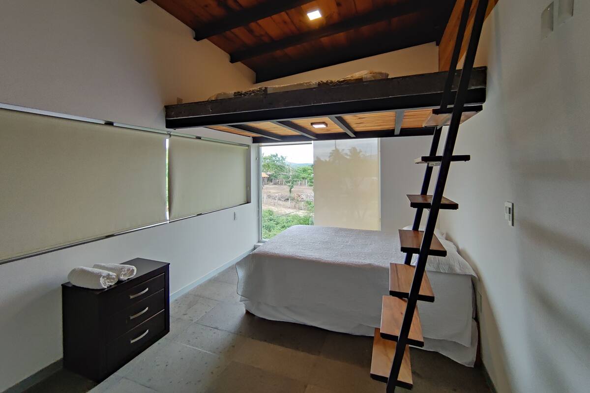 Een kleine kamer met een stapelbed, een bureau en een kledingkast.