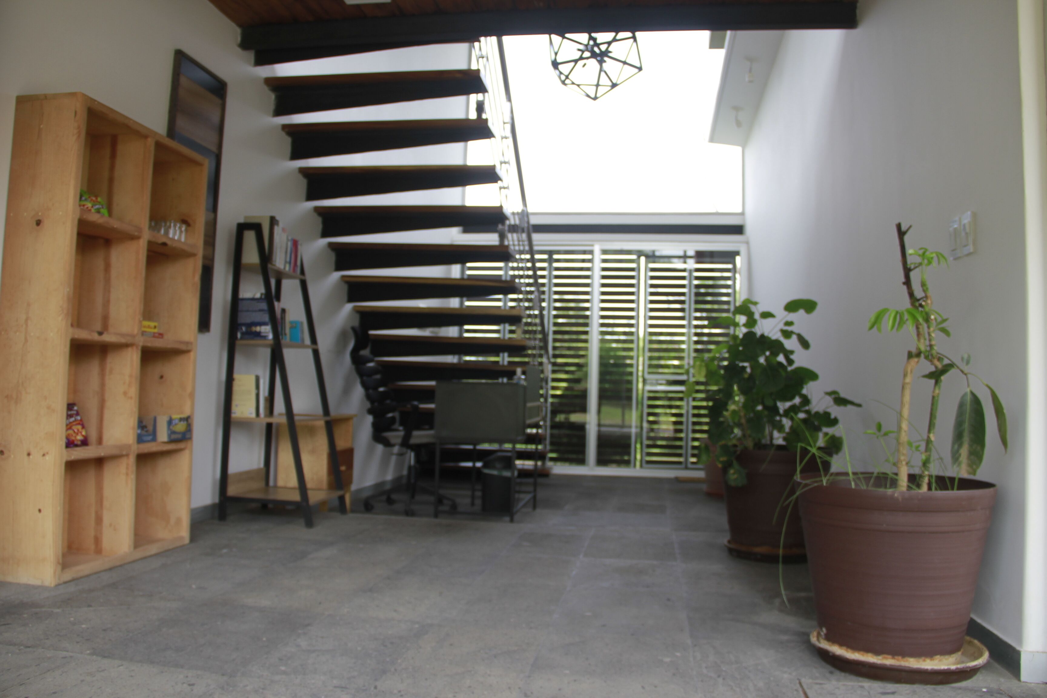 A modern interior with a wooden bookshelf, a desk, and a potted plant.