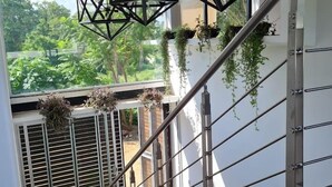A staircase with a metal railing, geometric hanging lights, and potted plants.