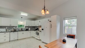 A modern kitchen with white cabinets, a wooden dining table, and a hanging light fixture. - Pet-Friendly Bluegrass Retreat w/ Fenced Yard (Georgetown)