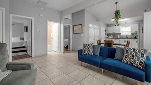 A modern living room with a blue sofa, a grey armchair, and a dining area with a kitchen in the background. - Pet-Friendly Bluegrass Retreat w/ Fenced Yard (Georgetown)