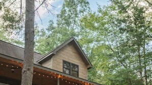 A two-story lodge with a wooden exterior, a balcony on the upper floor, and a staircase leading to the entrance. - Amazing Mountain Views + Hot Tub (Blue Ridge)