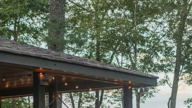 A wooden deck with a hammock and string lights, surrounded by trees. - Amazing Mountain Views + Hot Tub (Blue Ridge)