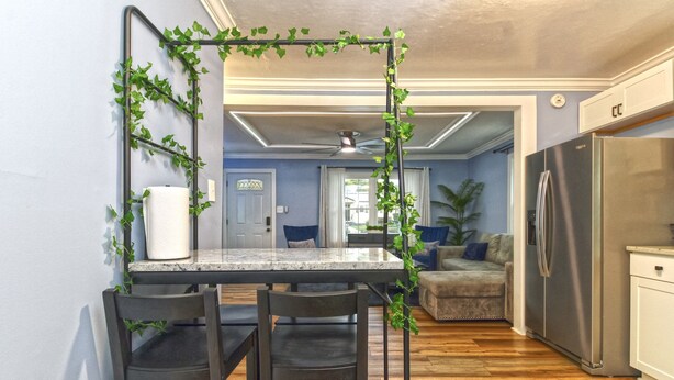 A kitchen with a marble countertop, two chairs, a refrigerator, and a dining area with a ceiling fan. - Cozy 3bdrm 2ba mins from Downtown (Greensboro)