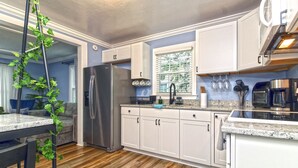 A modern kitchen with white cabinets, a stainless steel refrigerator, and a granite countertop. - Cozy 3bdrm 2ba mins from Downtown (Greensboro)