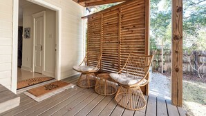 Un porche cubierto con sillas de mimbre y una pérgola de madera.