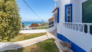 A coastal building with a white and blue facade, a balcony with white balustrades, and a view of the sea. - Casa Sardine by Acasadascasas (Mafra)