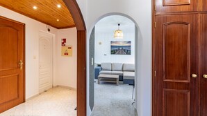 A hallway with wooden doors, a bench, a painting of a sunset, and a fire safety sign. - Casa Sardine by Acasadascasas (Mafra)