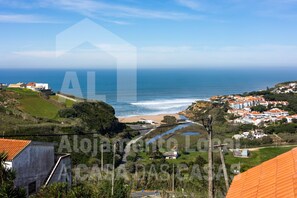 A coastal landscape with houses, a beach, and a view of the ocean. - Casa Sardine by Acasadascasas (Mafra)